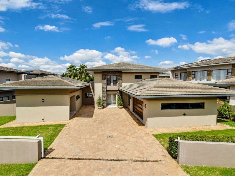 A modern double-story residential home featuring a paved driveway, double garage, and attractive stone cladding accents on the front facade.