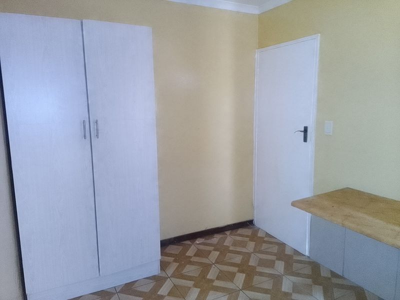 A bedroom featuring built-in wardrobe storage, a built-in desk area, and patterned floor tiles.