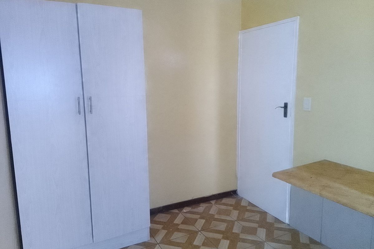 A bedroom featuring built-in wardrobe storage, a built-in desk area, and patterned floor tiles.