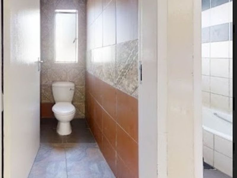 A functional bathroom featuring a toilet and bathtub with tiled walls and flooring, offering a clean and practical layout.