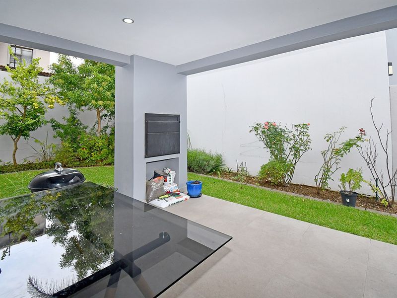 Covered patio area featuring a built-in braai, tiled flooring, and direct access to a private garden space.