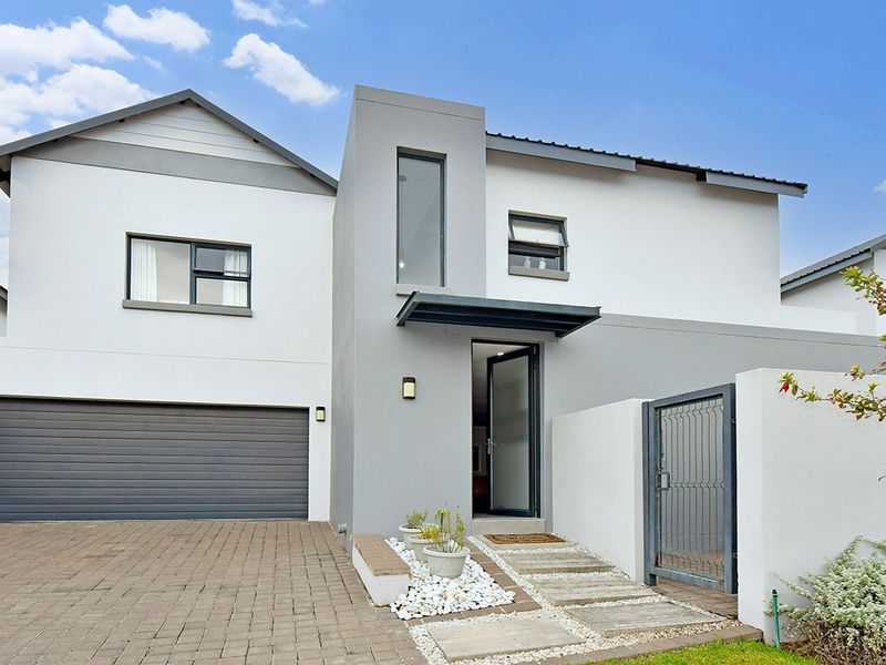 Modern double-story residential facade featuring a paved driveway, integrated double garage, and a welcoming pedestrian entrance with contemporary architectural finishes.