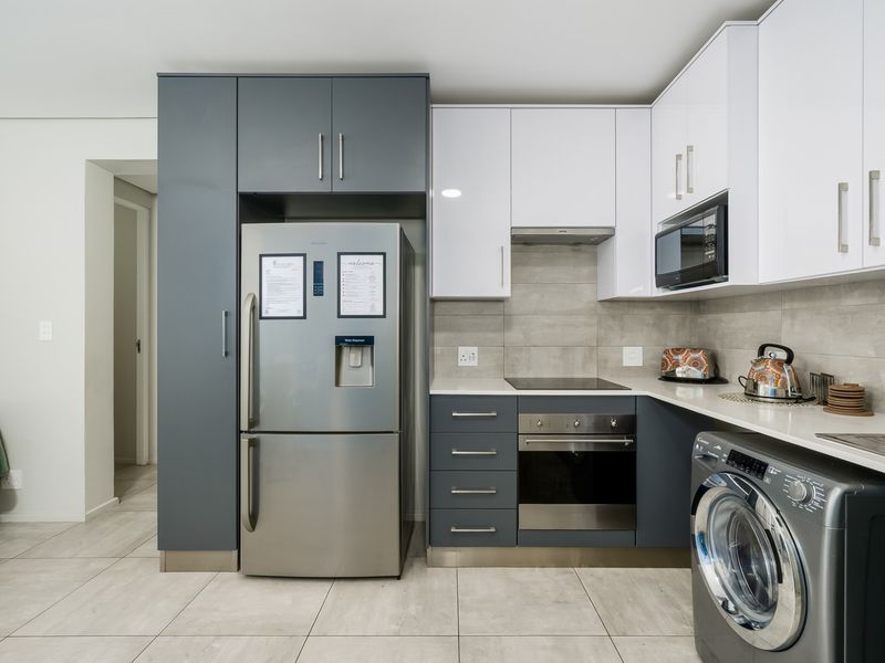 Modern kitchen featuring two-tone cabinetry, stone countertops, integrated appliances, and sleek tiled finishes, offering a clean and functional culinary space.