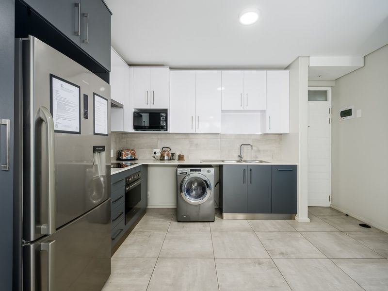 Modern kitchen featuring two-tone cabinetry, stone countertops, integrated appliances, and tiled flooring, offering a clean and functional workspace.