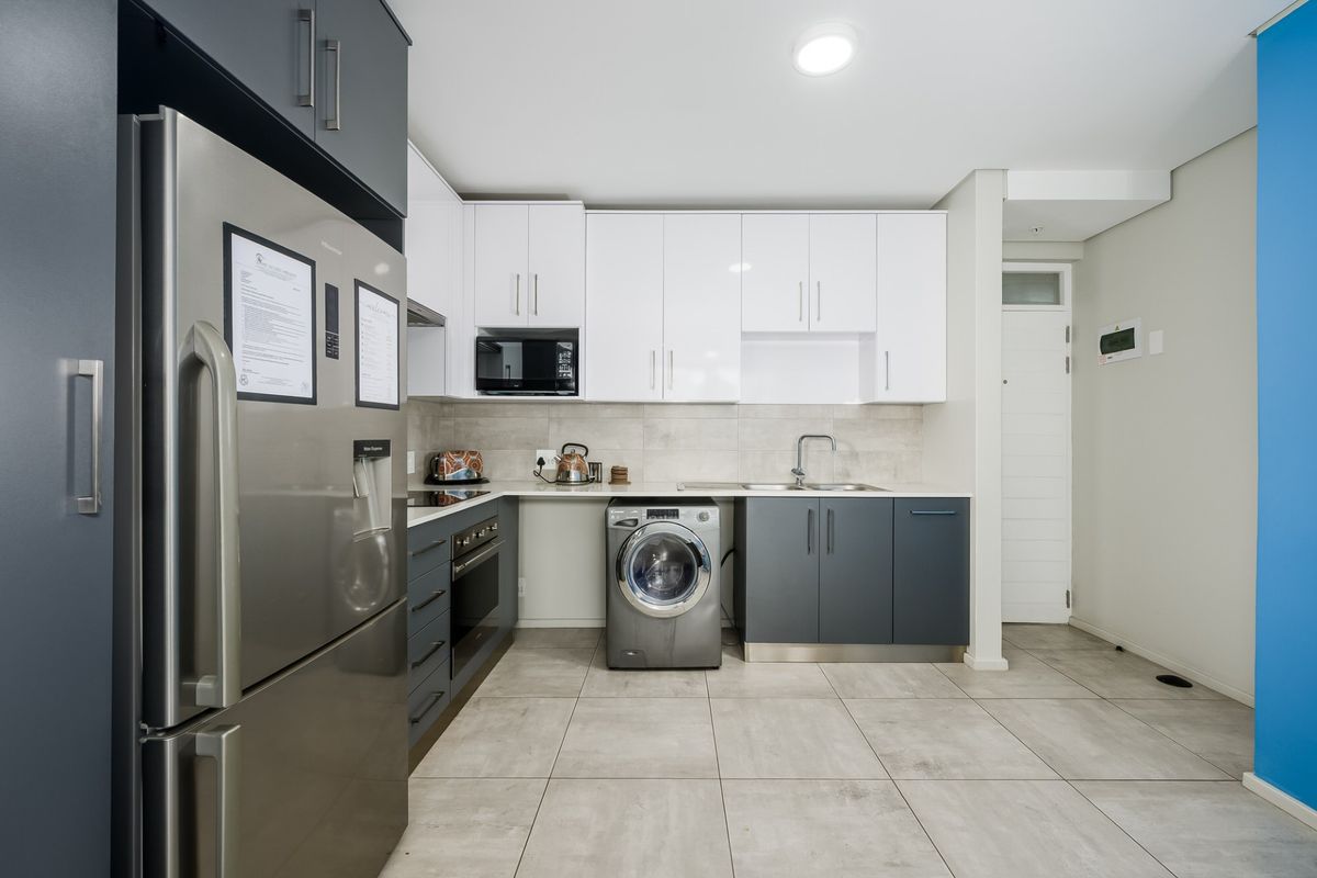 Modern kitchen featuring two-tone cabinetry, stone countertops, integrated appliances, and tiled flooring, offering a clean and functional workspace.