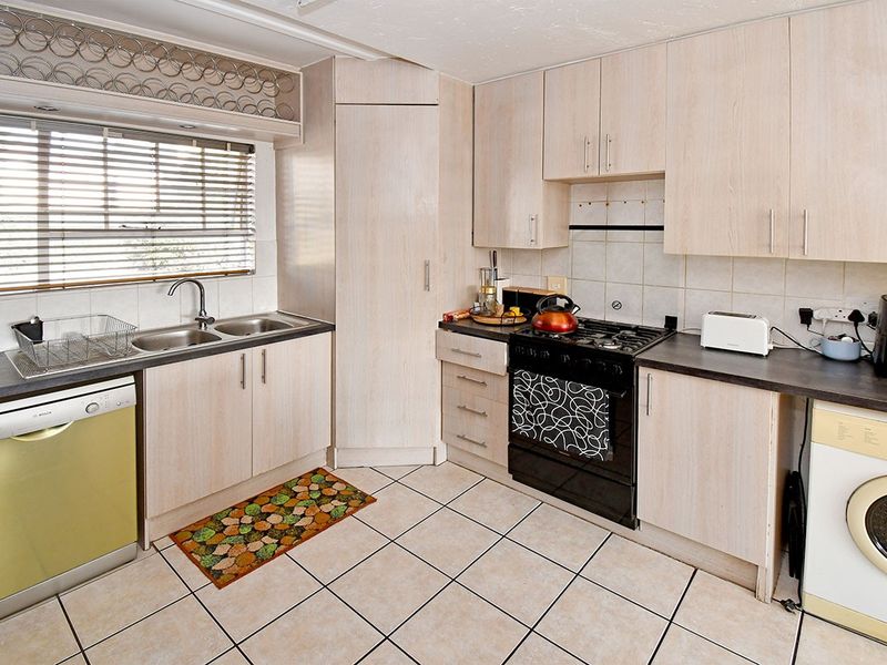 Functional kitchen featuring light-toned laminate cabinetry, tiled flooring, a gas cooktop, and a double bowl stainless steel sink with integrated wine storage above.
