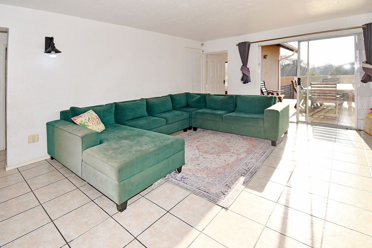 Spacious living room featuring ceramic floor tiles and a large sliding glass door providing direct access to the outdoor patio area.