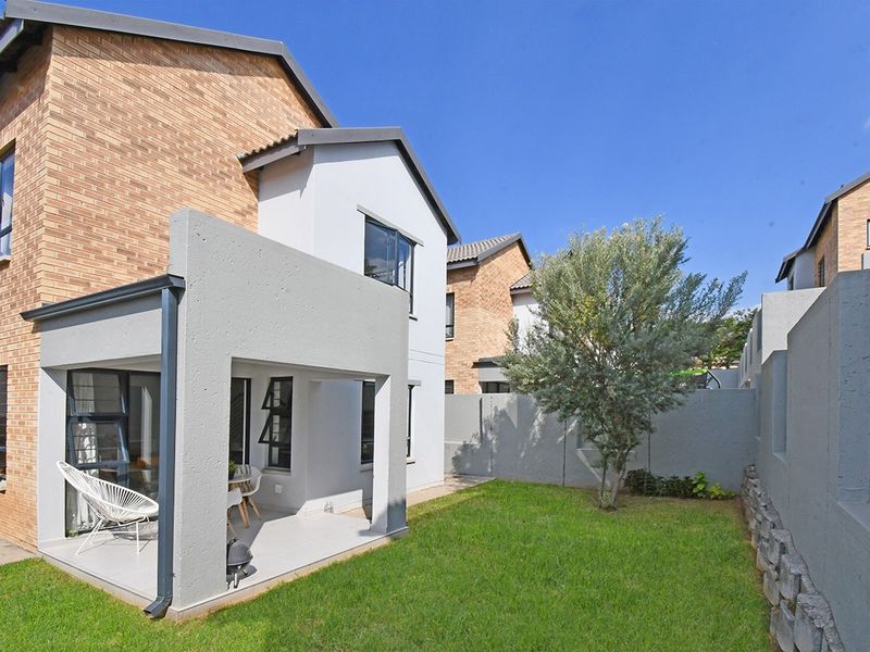 Rear view of the property featuring a covered patio with tiled flooring, a private garden, and a combination of brick and plastered exterior walls.