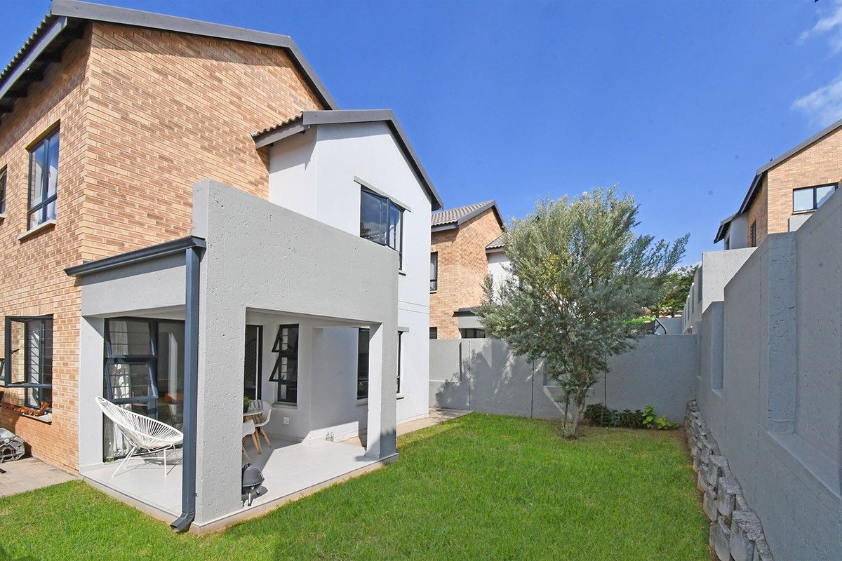 Rear view of the property featuring a covered patio with tiled flooring, a private garden, and a combination of brick and plastered exterior walls.