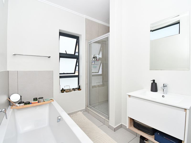 Modern bathroom featuring a bathtub, separate shower enclosure, and a contemporary vanity unit with a basin and wall-mounted mirror.
