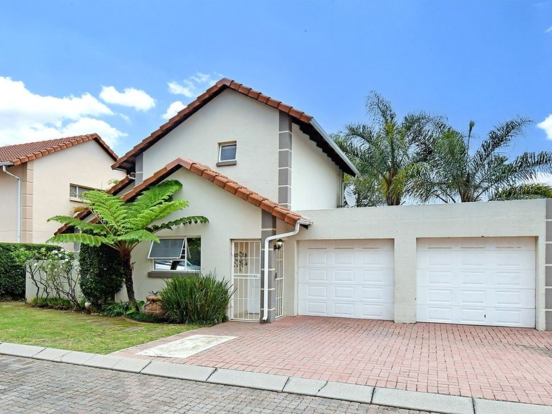 Front view of a well-maintained residential property featuring a double garage, paved driveway, and tiled roof.