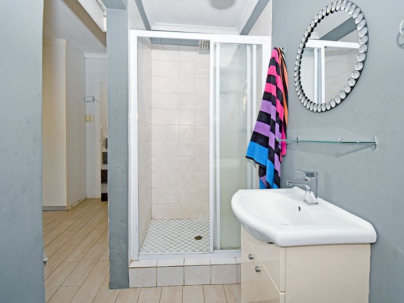A functional bathroom featuring a shower enclosure, a vanity cabinet with a washbasin, and tiled flooring.