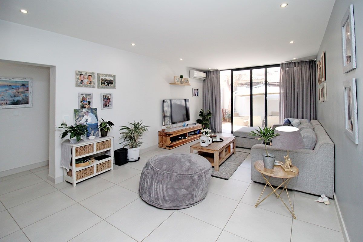 Bright and spacious living room featuring neutral tiled flooring, recessed downlighting, and large sliding glass doors providing access to the outdoor area.