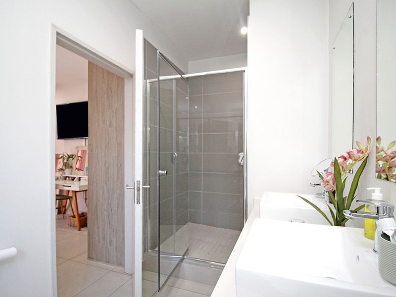 Modern bathroom featuring a walk-in shower with glass enclosure, double vanity sinks, and large wall-mounted mirrors.