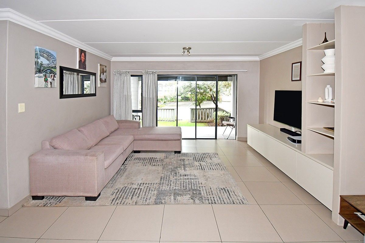 Spacious living room featuring neutral tiled flooring, built-in shelving, and large sliding glass doors providing access to the outdoor area.