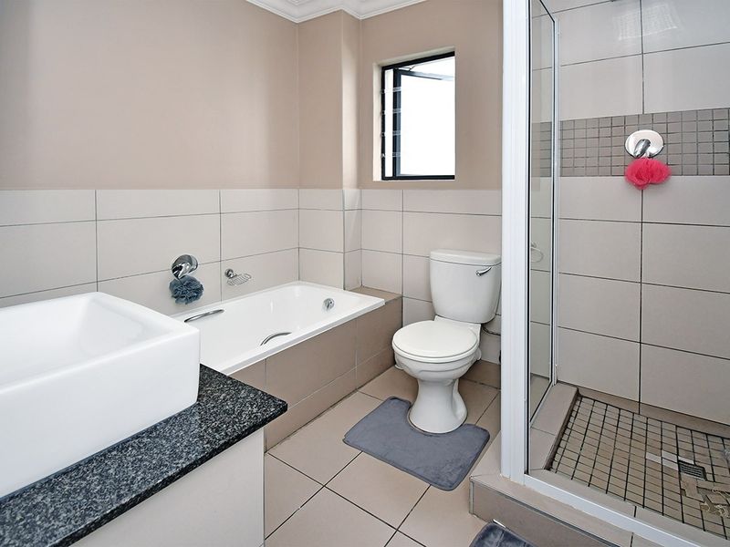 A well-maintained bathroom featuring a built-in bathtub, separate shower enclosure, toilet, and a vanity basin with a granite countertop.