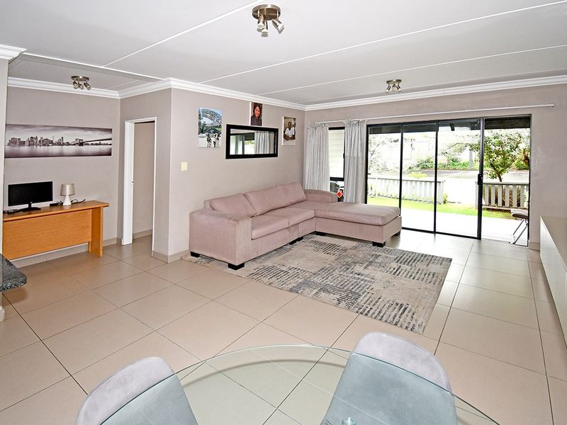 Spacious open-plan living area featuring neutral tiled flooring, coved ceilings, and large sliding glass doors providing access to the outdoor patio area.