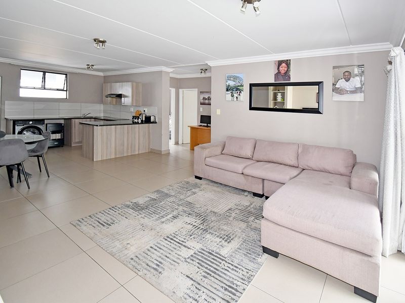 Spacious open-plan living area featuring a modern kitchen with built-in cabinetry, island, and tiled flooring throughout, creating a seamless flow for daily living.