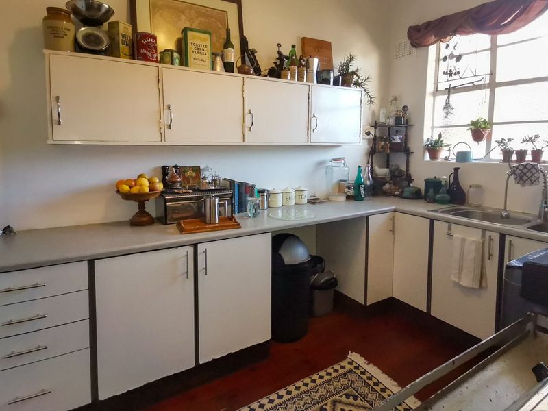A functional kitchen featuring white cabinetry, laminate countertops, and a stainless steel sink, offering a classic layout with potential for modern updates.