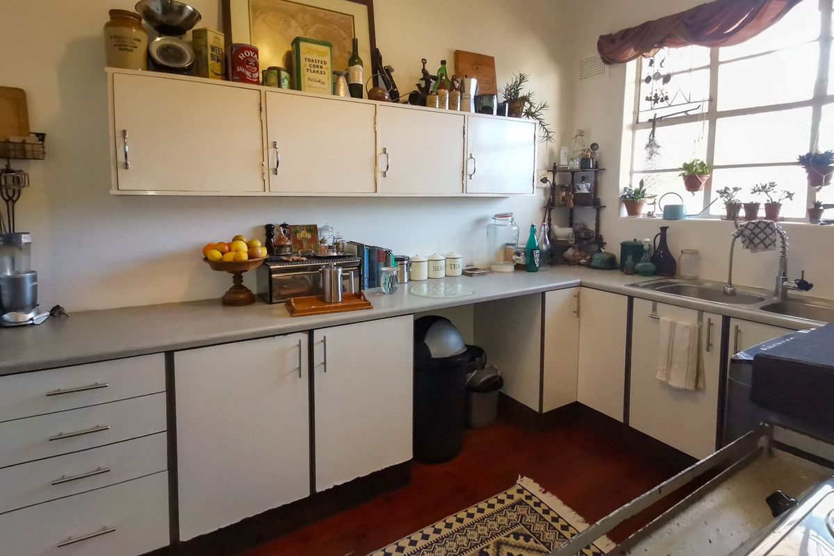A functional kitchen featuring white cabinetry, laminate countertops, and a stainless steel sink, offering a classic layout with potential for modern updates.