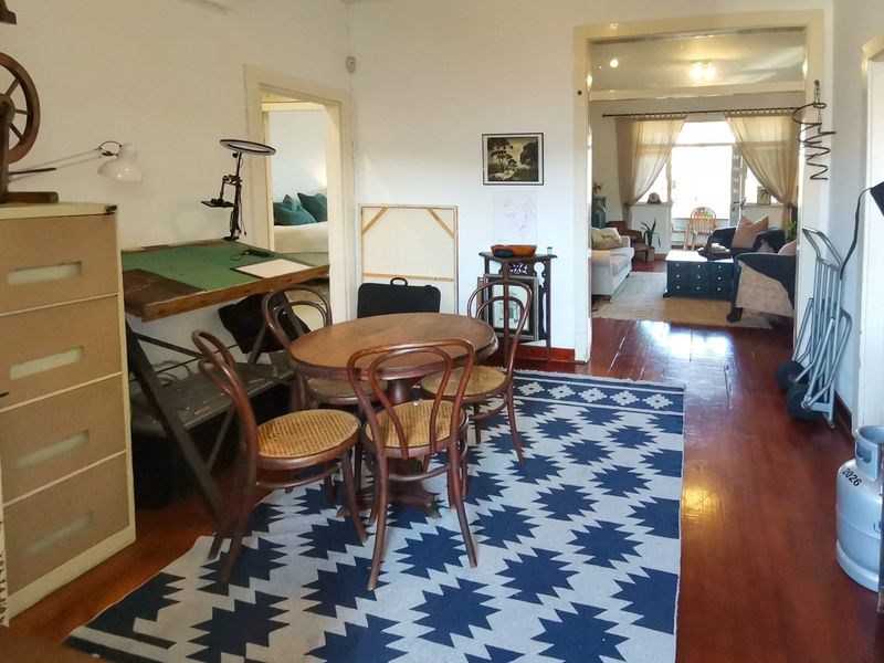 A living area featuring polished hardwood flooring and connecting doorways leading to adjacent rooms, providing a versatile and open layout.