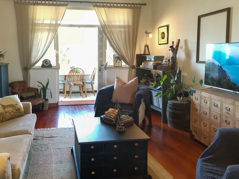 A cozy living room featuring polished hardwood flooring and a sliding glass door that provides access to an outdoor patio area.