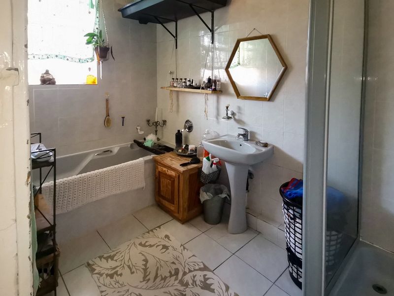 A functional bathroom featuring a pedestal basin, bathtub, and separate shower enclosure with tiled finishes throughout.
