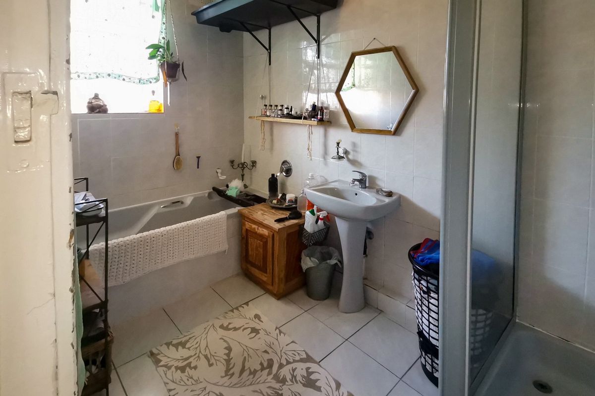 A functional bathroom featuring a pedestal basin, bathtub, and separate shower enclosure with tiled finishes throughout.
