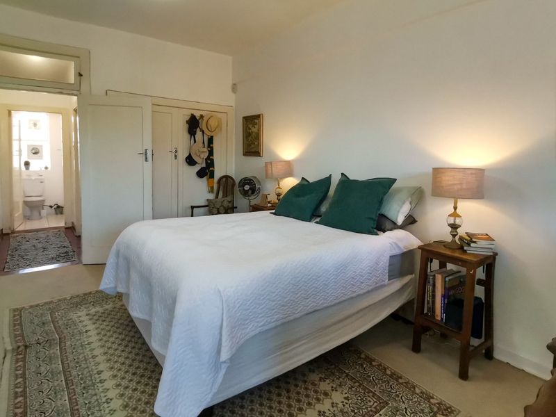 A well-lit bedroom featuring built-in cupboards and a transom window, with an adjoining view into a bathroom area.
