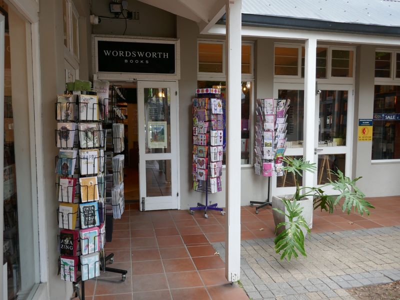 Front entrance of a retail bookstore featuring a covered tiled walkway, glass-paneled doors, and large display windows.