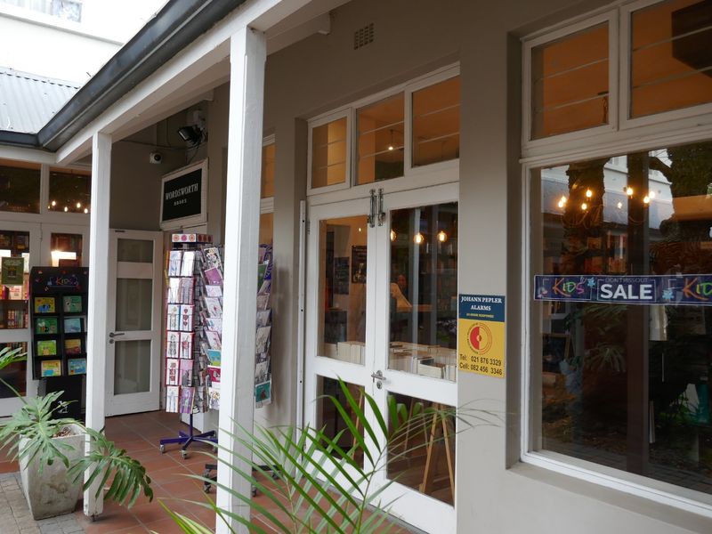 Front entrance of a retail bookstore featuring a covered walkway, terracotta tiling, and large glass display windows.