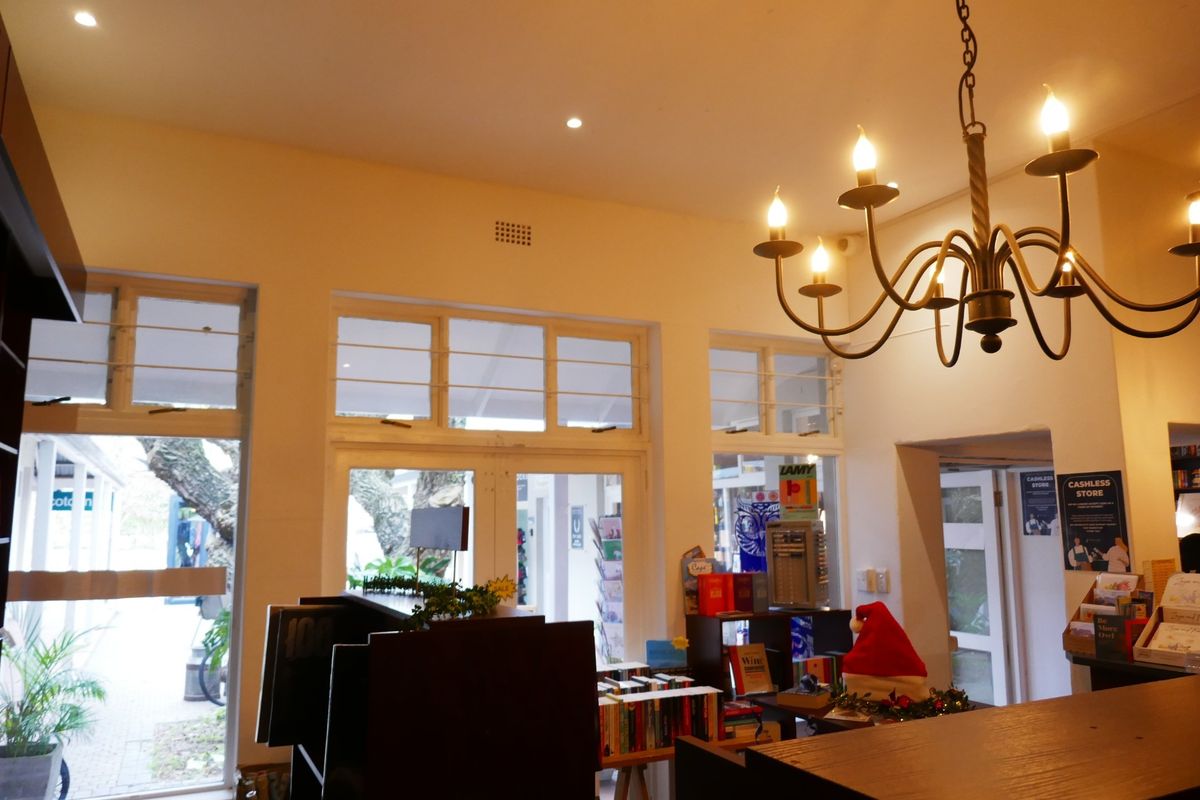 Interior retail space featuring high ceilings, classic wrought iron chandelier lighting, and large timber-framed windows providing natural light and views of the exterior.