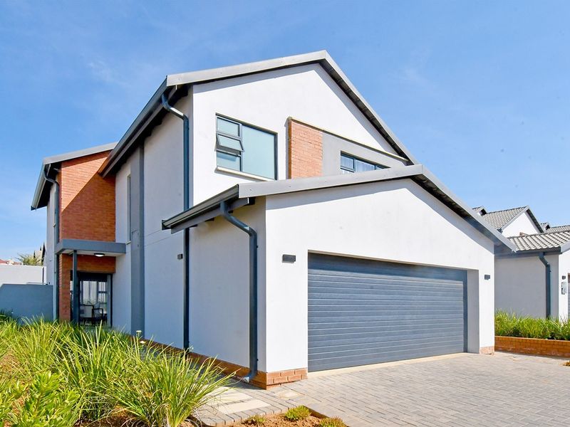 Modern double-storey residential home featuring a double garage, paved driveway, and a combination of brick and plastered exterior finishes.