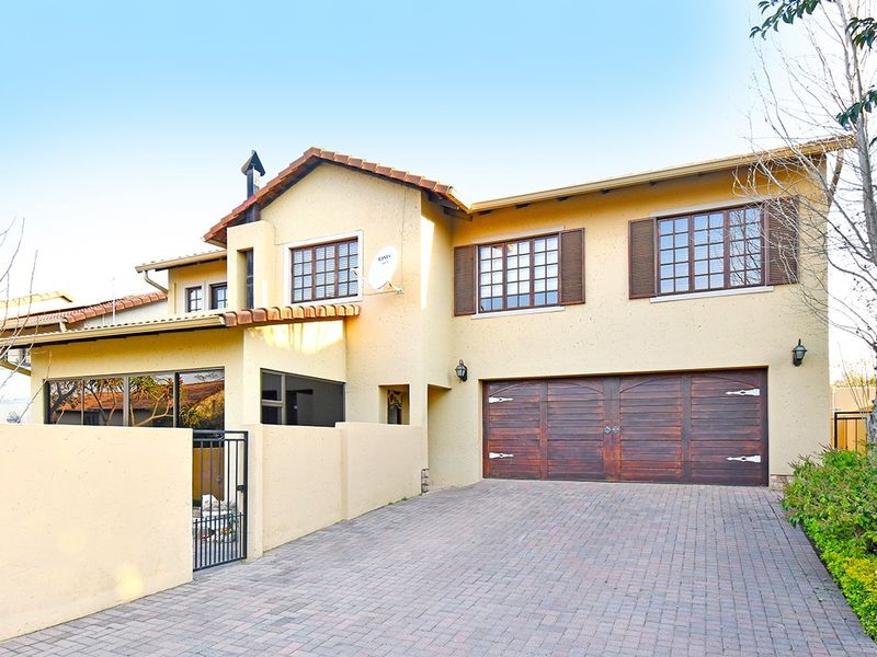 Front elevation of a two-story house featuring a paved driveway, double garage with timber doors, and a walled entrance.