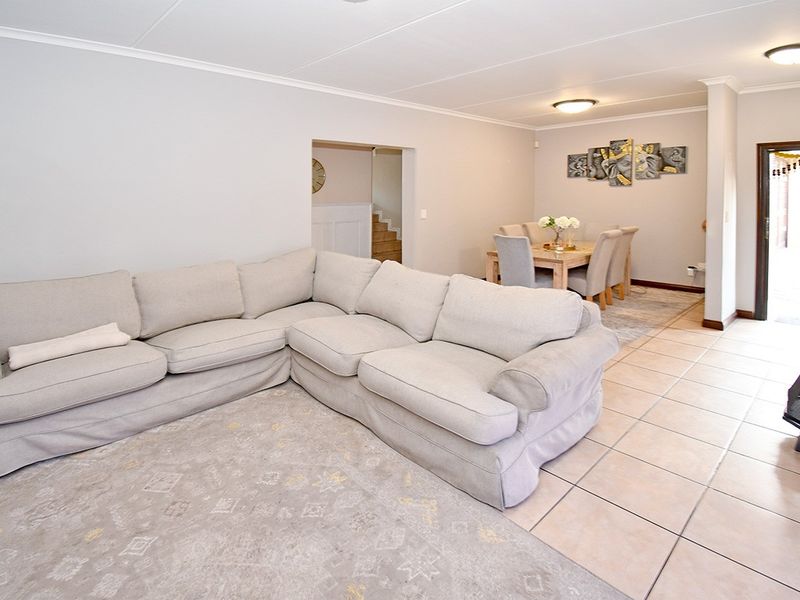 Spacious open-plan living and dining area featuring neutral tiled flooring, coved ceilings, and a built-in fireplace, creating a comfortable and functional layout.