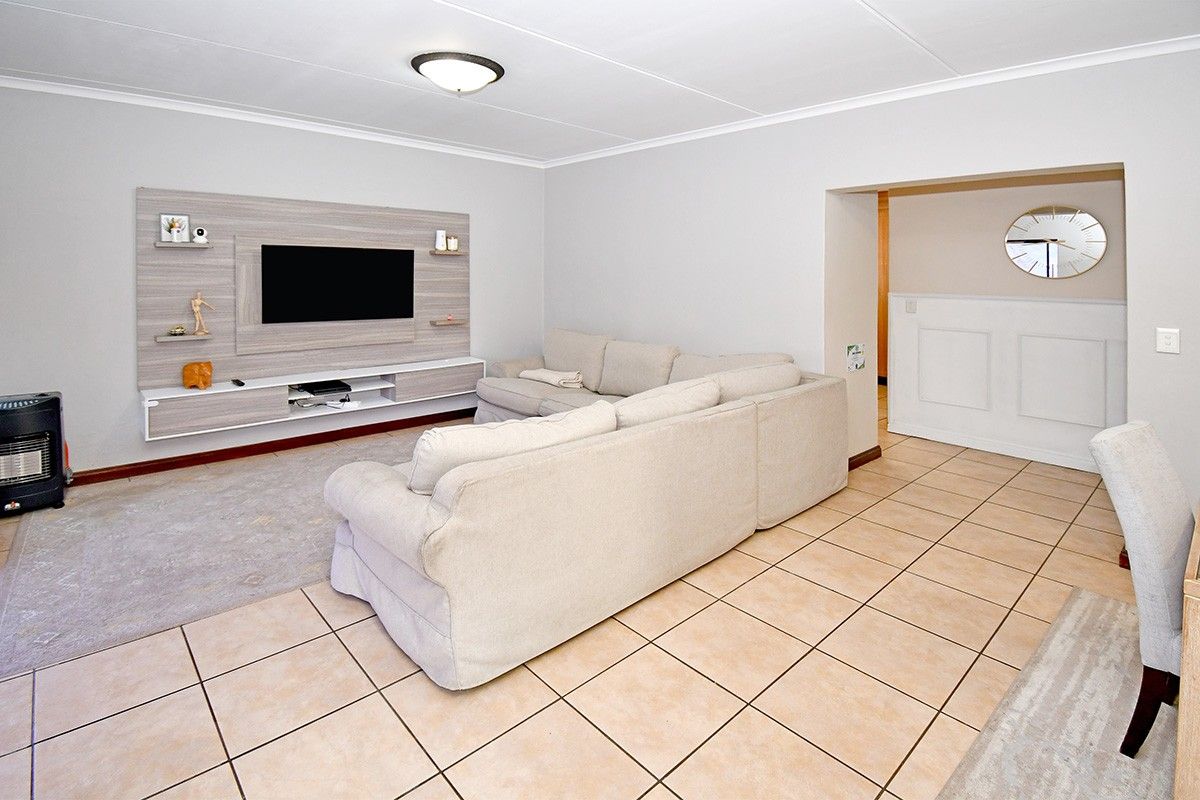 A spacious living room featuring tiled flooring, a modern built-in media unit, and wainscoting detail, offering a comfortable and functional living space.