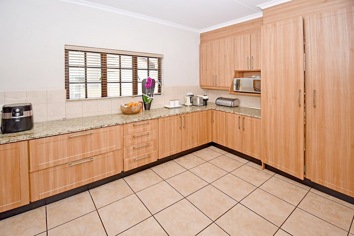 A well-maintained kitchen featuring light wood-finish cabinetry, granite countertops, tiled flooring, and a tiled backsplash with integrated microwave housing.