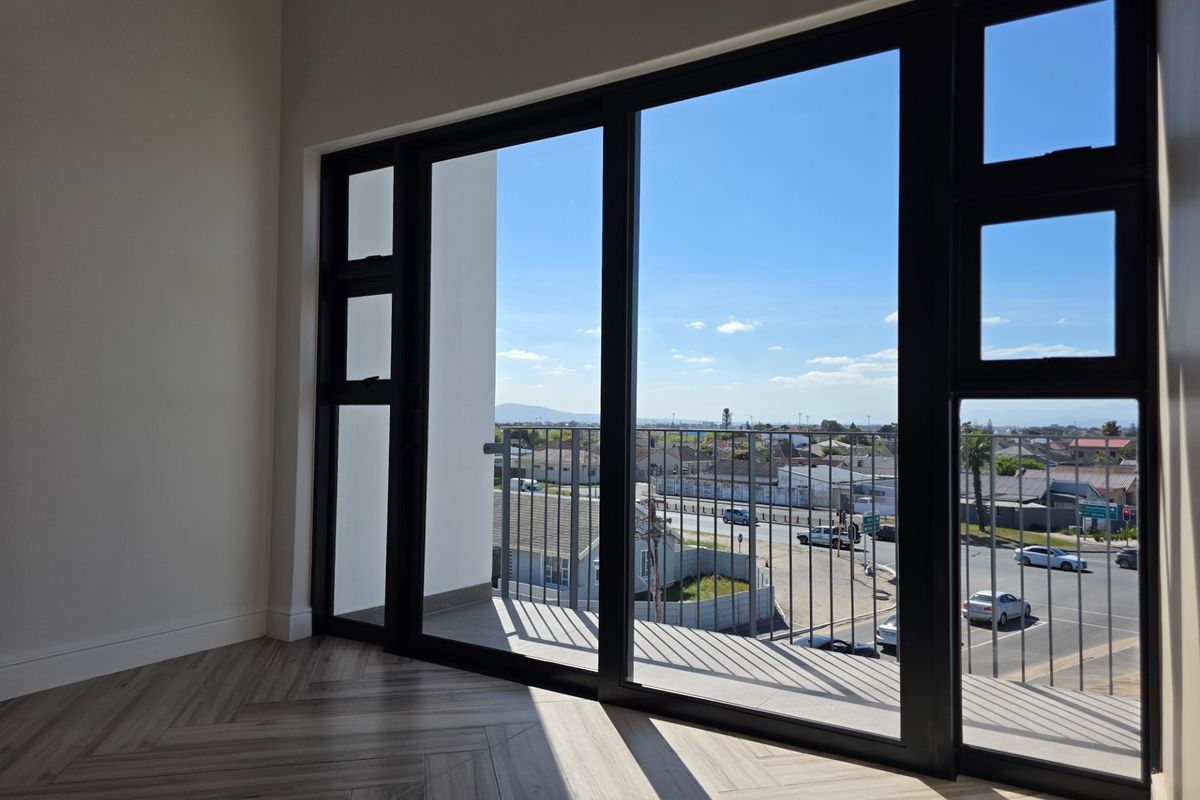 Bright living area featuring modern herringbone flooring and large sliding glass doors opening onto a balcony with expansive neighborhood views.