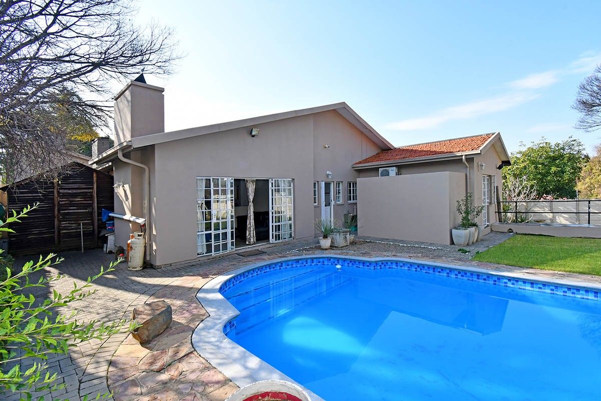 Rear view of the house featuring a swimming pool, paved patio area, and direct access to the living space through sliding glass doors.