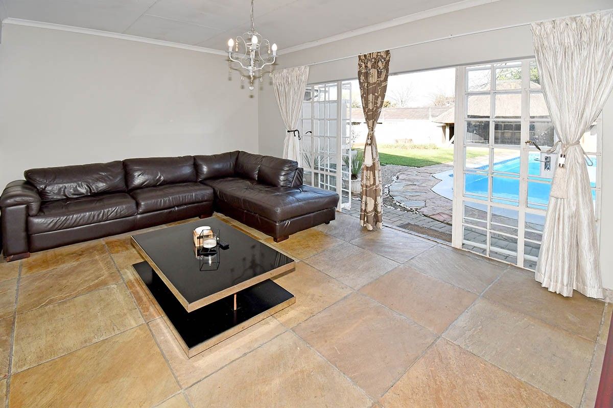 Spacious living room featuring large stone floor tiles and double french doors providing direct access to the outdoor pool area.