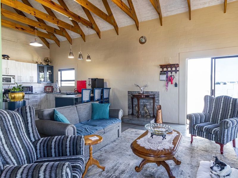 Spacious open-plan living area featuring a vaulted ceiling with exposed timber rafters, a built-in fireplace, and an integrated kitchen with island seating.