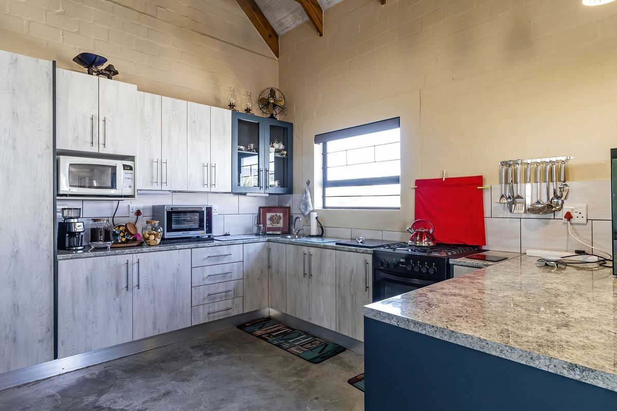 A well-appointed kitchen featuring light wood-grain cabinetry, granite countertops, a gas stove, and exposed timber rafters, offering a functional and modern workspace.