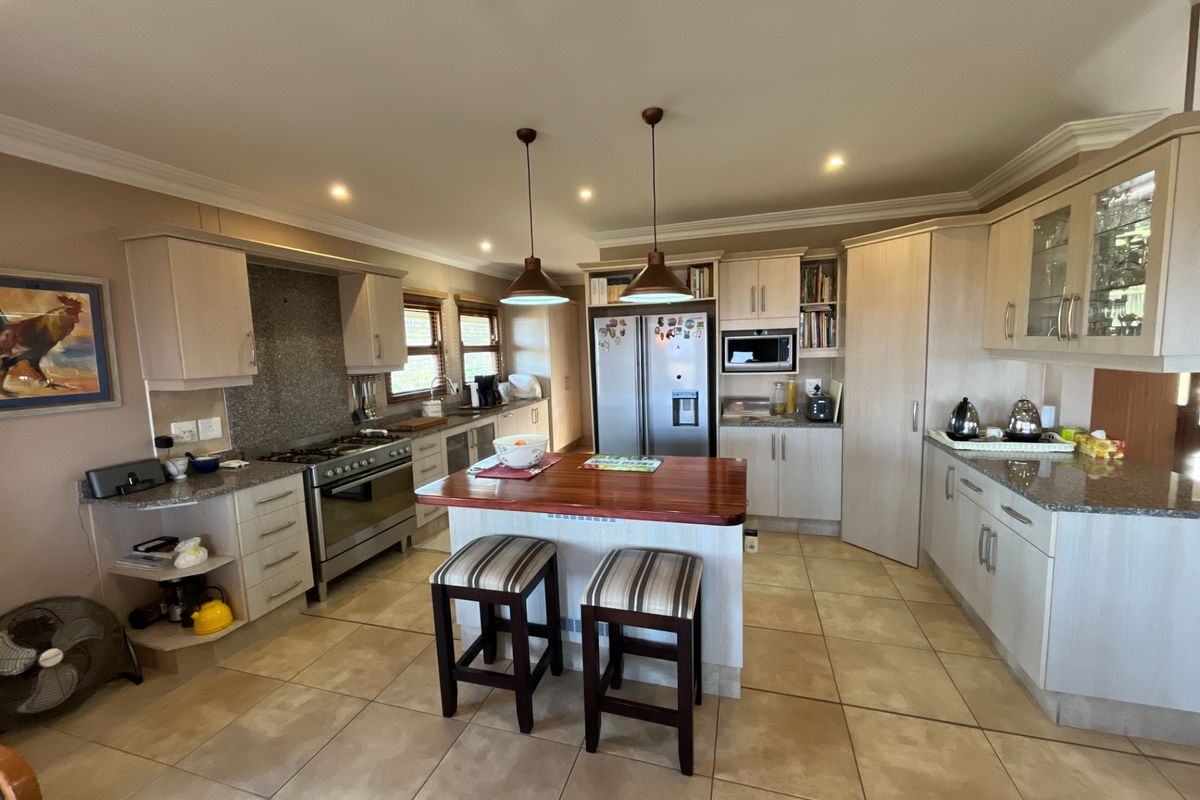 Spacious kitchen featuring light wood cabinetry, granite countertops, a central island with breakfast seating, and integrated appliances including a gas stove and oven.