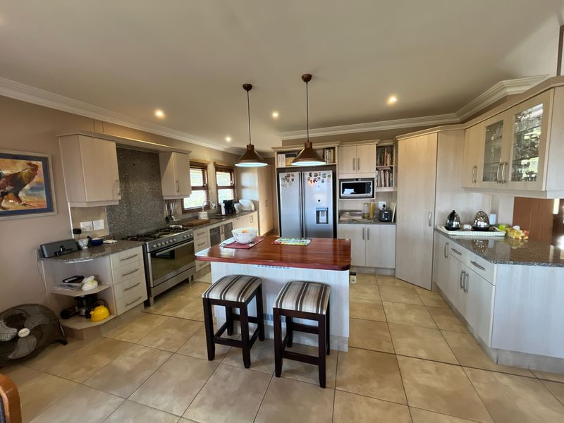 Spacious kitchen featuring light wood cabinetry, granite countertops, a central island with breakfast seating, and integrated appliances including a gas stove and oven.
