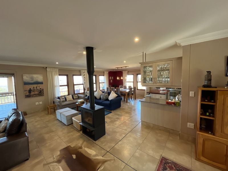 Spacious open-plan living and dining area featuring a central freestanding fireplace, tiled flooring, and a functional kitchen with granite countertops.