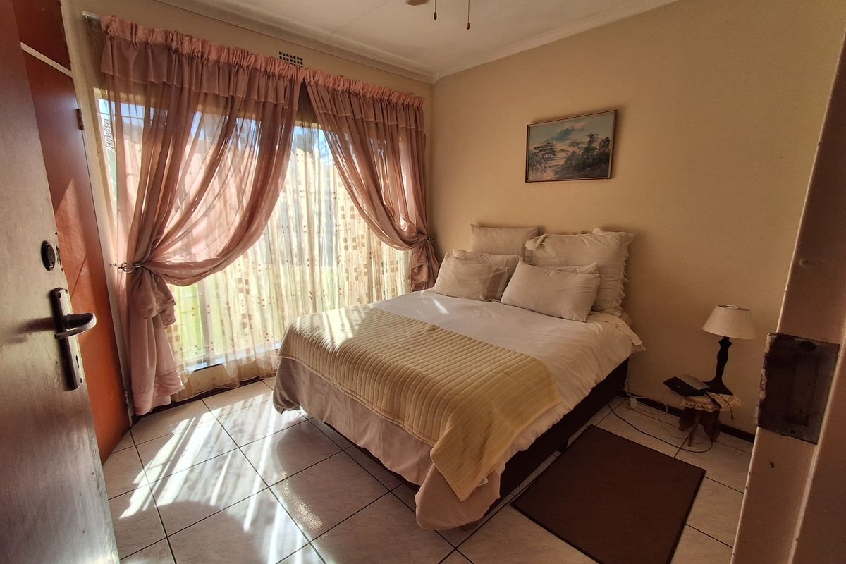 A bedroom featuring tiled flooring, a ceiling fan, and a sliding glass door providing natural light.