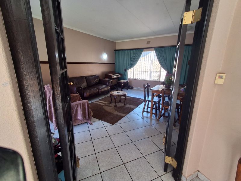 A living room featuring tiled flooring, a chair rail, and double french door entry, providing a functional and traditional living space.