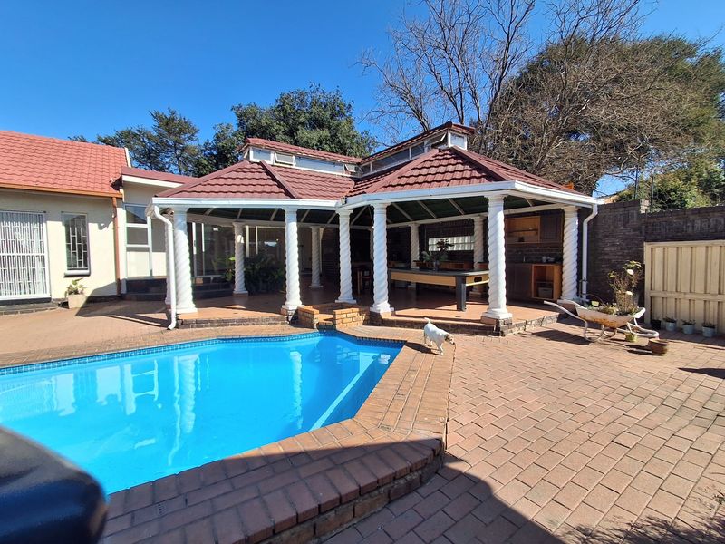Spacious outdoor entertainment area featuring a swimming pool, brick-paved patio, and a covered gazebo structure with built-in cabinetry.