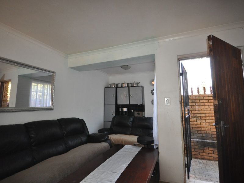 A living room area featuring built-in cabinetry and direct access to an exterior space through a timber door and security gate.