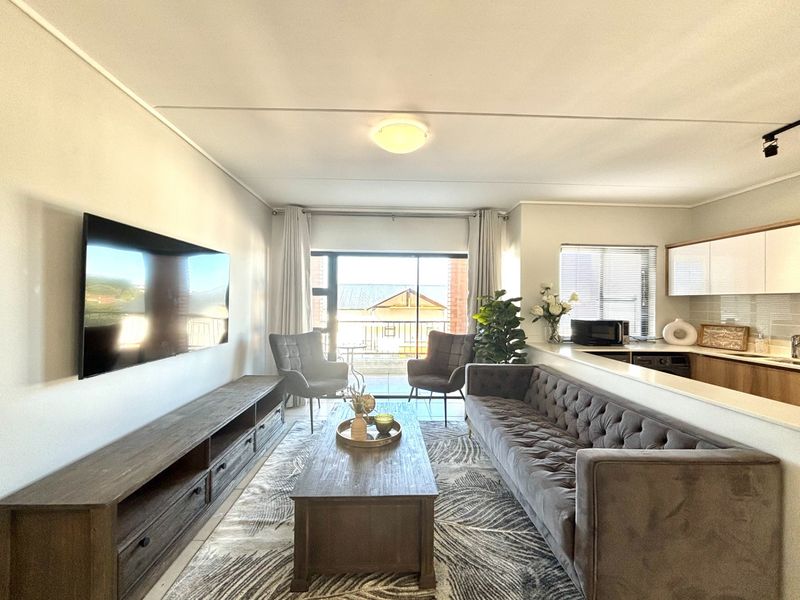 Open-plan living area featuring a modern kitchen with sleek cabinetry and a seamless transition to a balcony through large sliding glass doors.